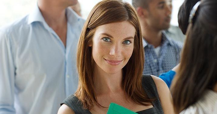 A woman smiling into the camera with other employees out of focus behind her.