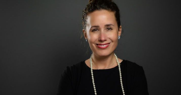 Elizabeth Blass, graduate of the Master of Science in Management, Strategy and Leadership program, smiling in front of a black backdrop wearing a black shirt and pearl necklace.