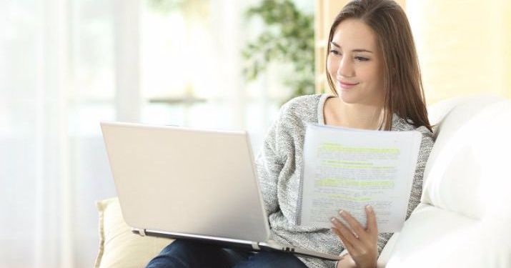 A woman using a laptop and spiral notebook with handwritten notes determining if a graduate certificate is worth it.