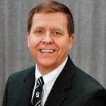 Joe Potchen, a visiting faculty member for MSU's Broad College of Business, smiling into the camera wearing a business suit and tie.