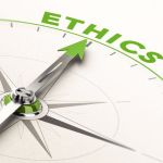 Close up of a compass with a green arrow pointing to the word "Ethics".