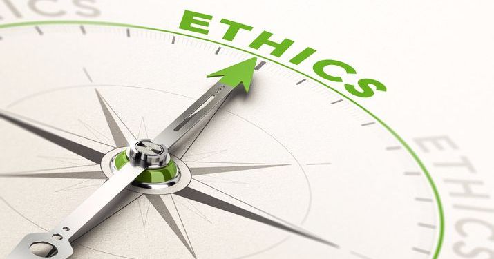Close up of a compass with a green arrow pointing to the word "Ethics".