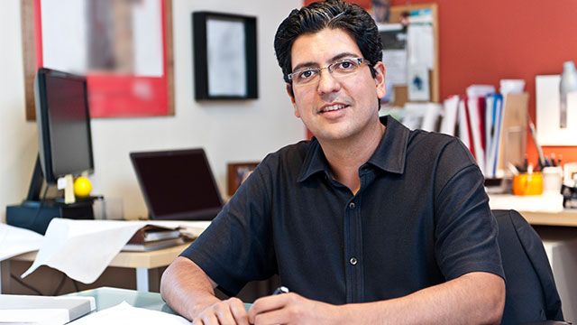 A man sitting at his desk in an office, smiling and talking about leadership.