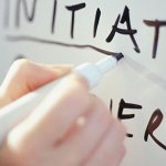 Close up of a hand writing out leadership skills on a whiteboard with a black dry erase marker.