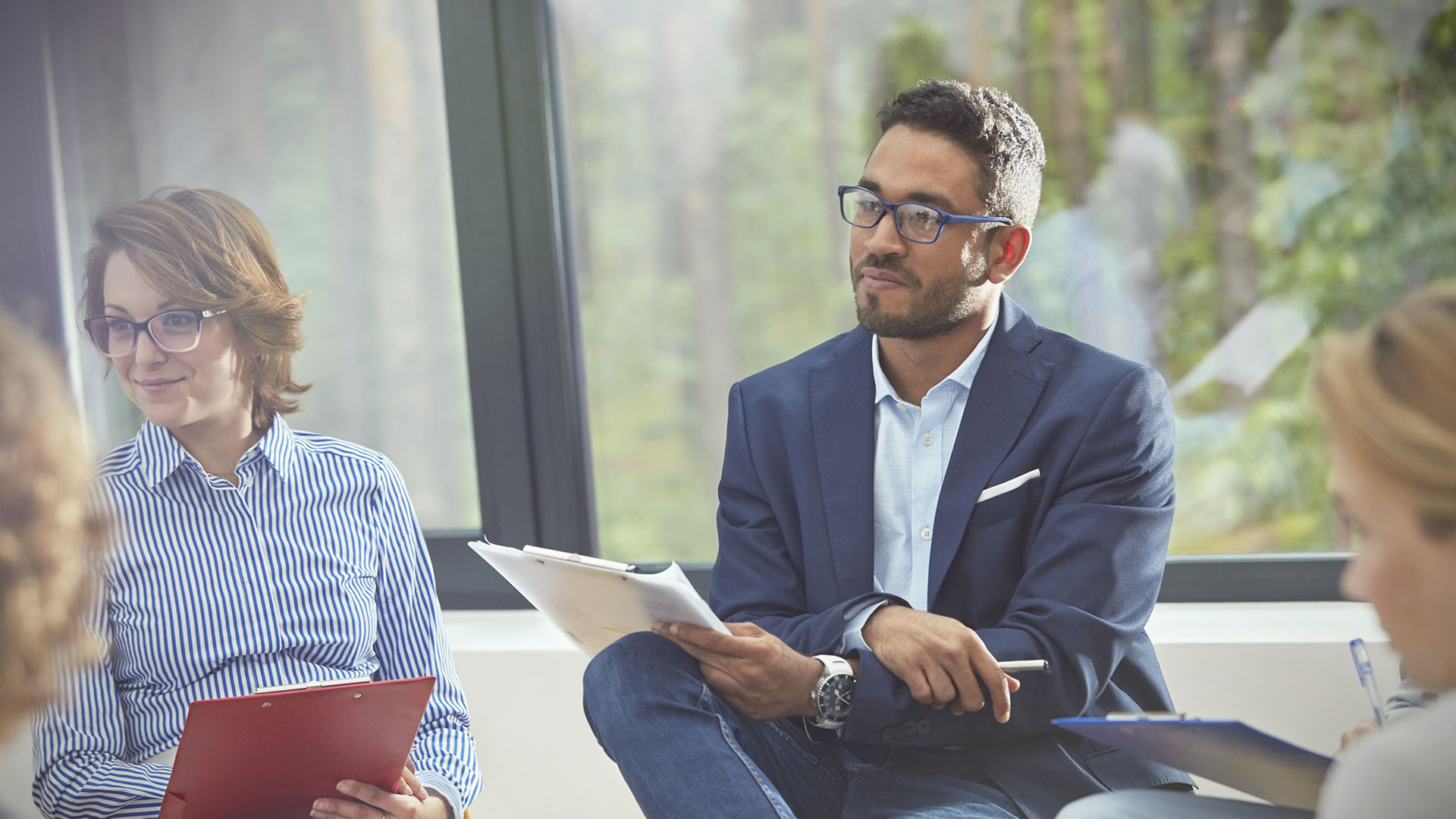 Office employees sitting together in a meeting, listening intently to someone speaking.