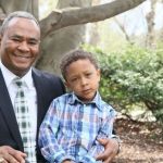 Albertus Kariko, graduate of MSU's MS in Management, Strategy and Leadership degree, sitting with his son on campus at MSU.