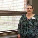 Kristi Kirkpatrick, MS in Management, Strategy and Leadership grad, standing and smiling in front of a window.