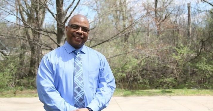 Ramar Scales, MS in Management, Strategy and Leadership grad, smiling in front of a forest.