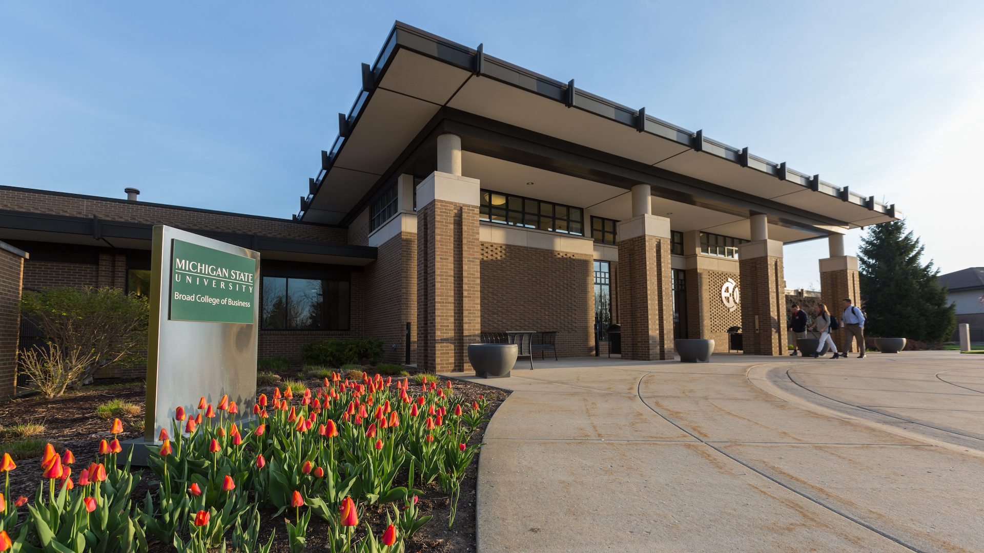 Broad College of Business building on MSU's campus with a few students walking in the front doors.