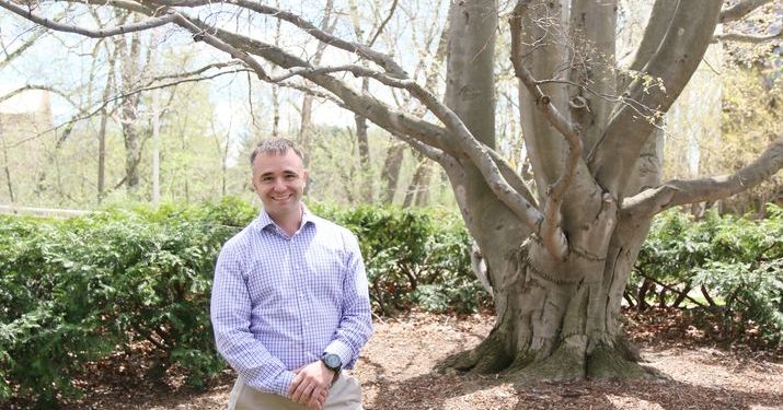 Matt McKenna, MS in Management, Strategy and Leadership Grad, smiling in front of a large tree on the MSU campus.