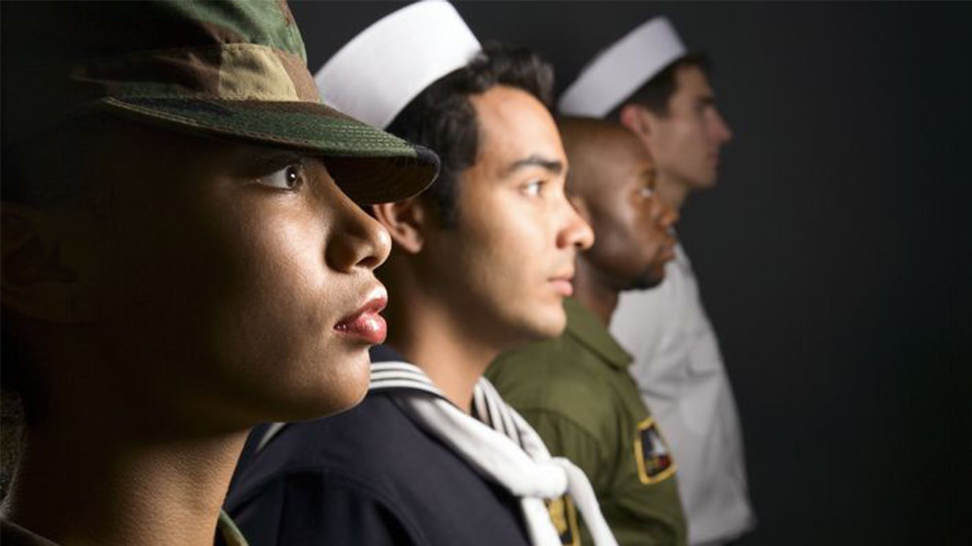 Four people in various military uniforms standing in a row.