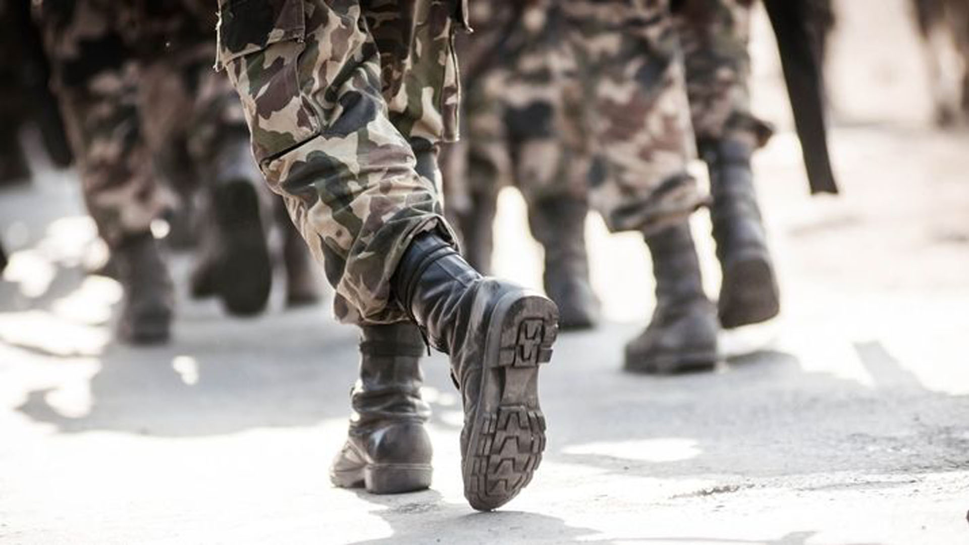 Close up of the boots of a group of military personnel walking in camouflage uniforms.