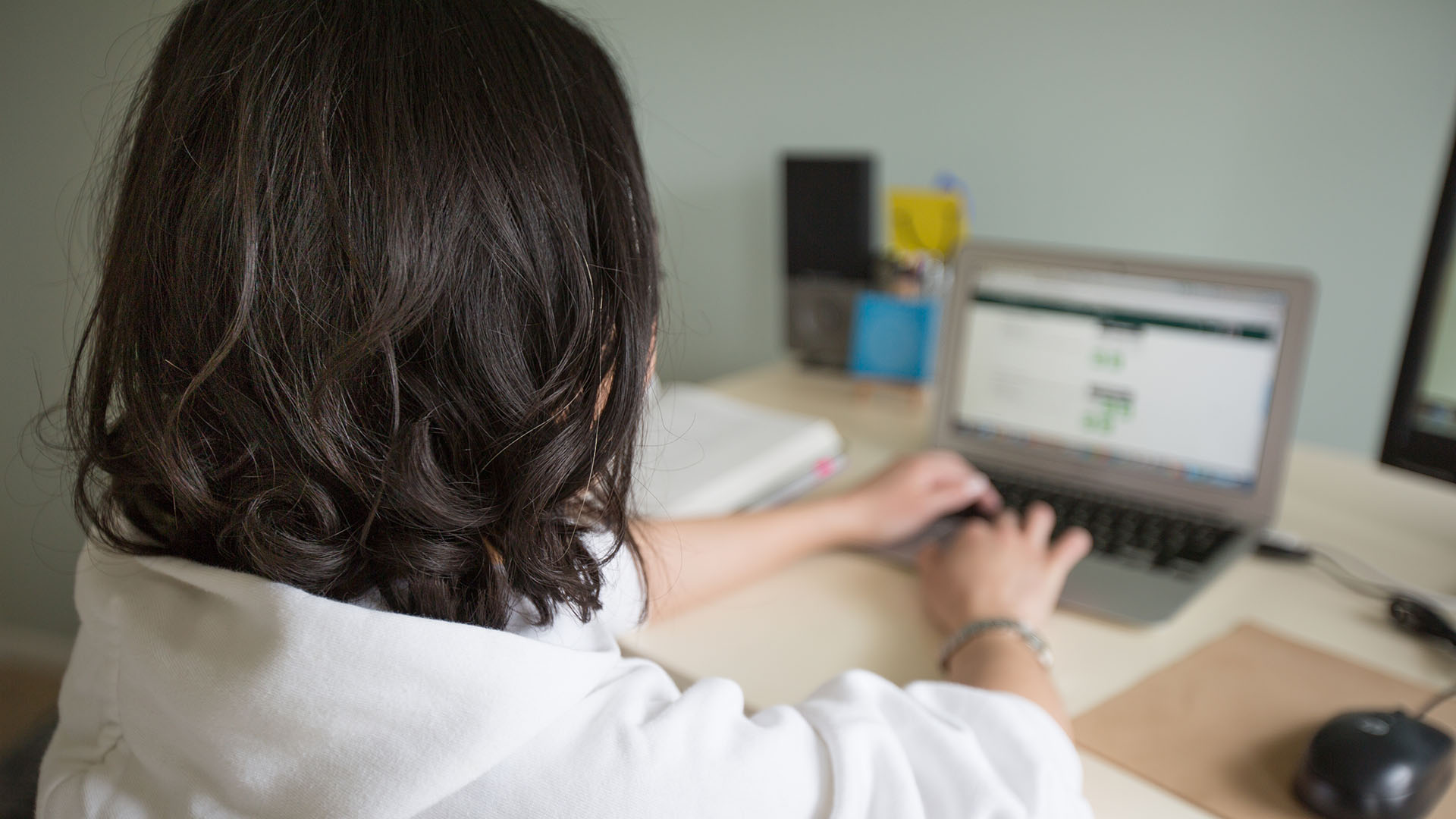 View from behind of a woman working on her laptop.