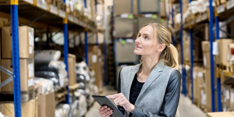 Female distribution manager reviewing digital tablet at warehouse.