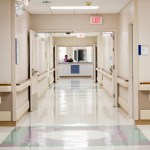 Empty hospital hall leading towards ward reception desk.