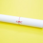 Rolled accreditation document tied with red string on yellow background.